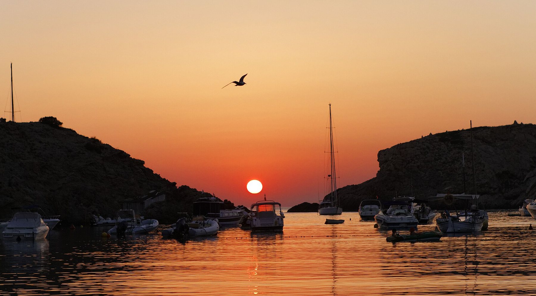Puesta de sol sobre una cala de Ibiza, con el sol tocando el horizonte